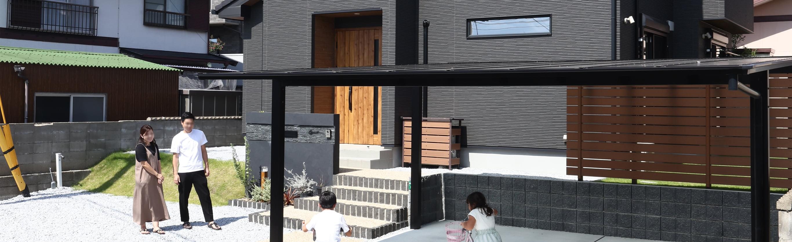 黒い外観で引き締まった印象の住まい。玄関まわりやフェンスにあしらった木目がぬくもりを添えています。手前にはたっぷり4台分の駐車スペースを確保